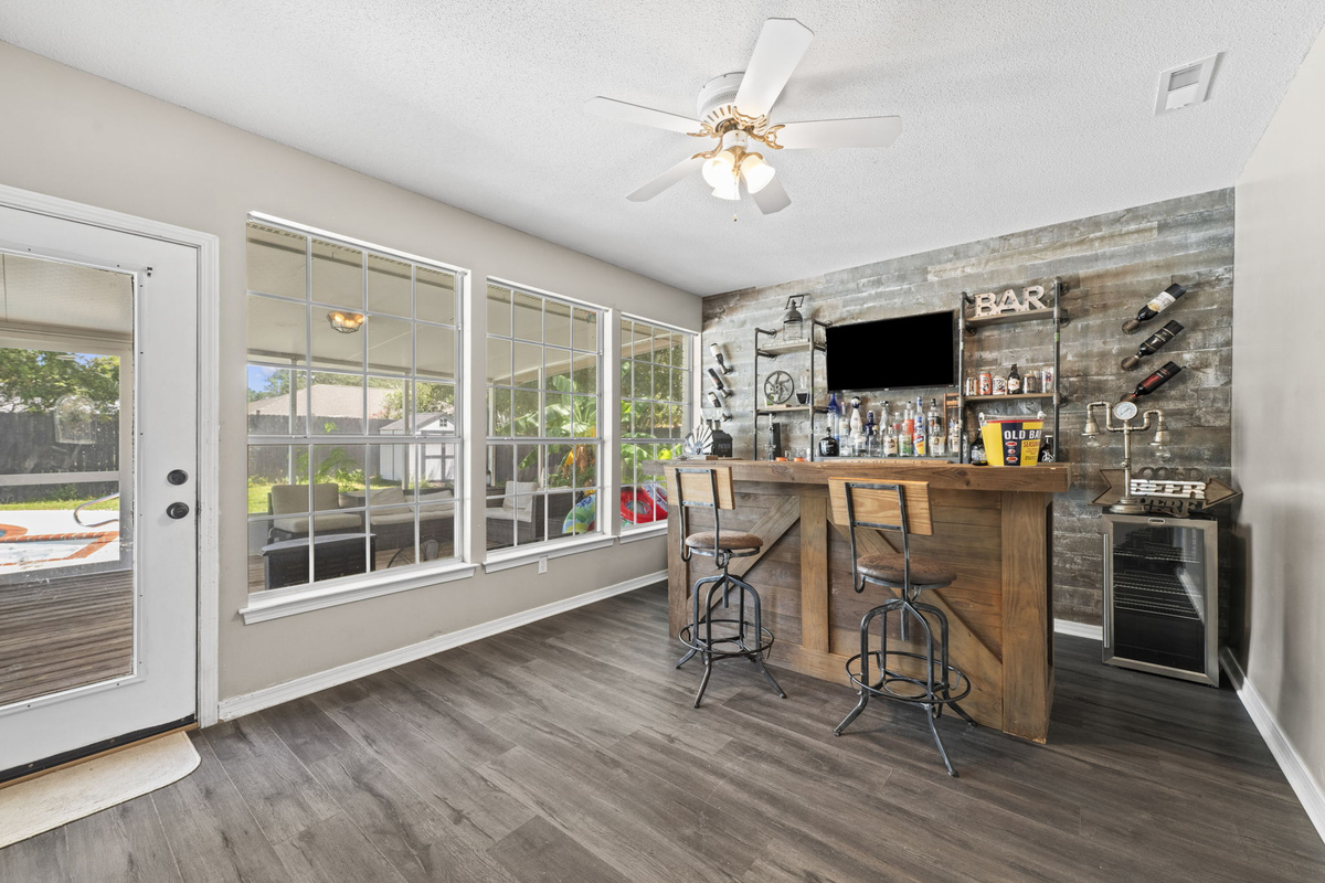 A rustic-chic indoor bar with barn wood accents, TV, and beverage fridge — perfect for game nights or happy hour.