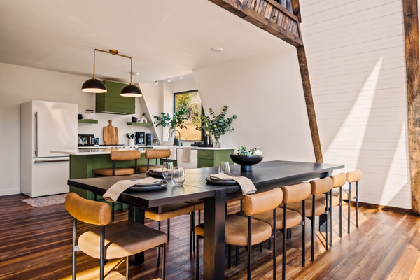 Seats 10+ around a grand dining table with leather chairs, soaring A-frame ceilings, and exposed timber beams