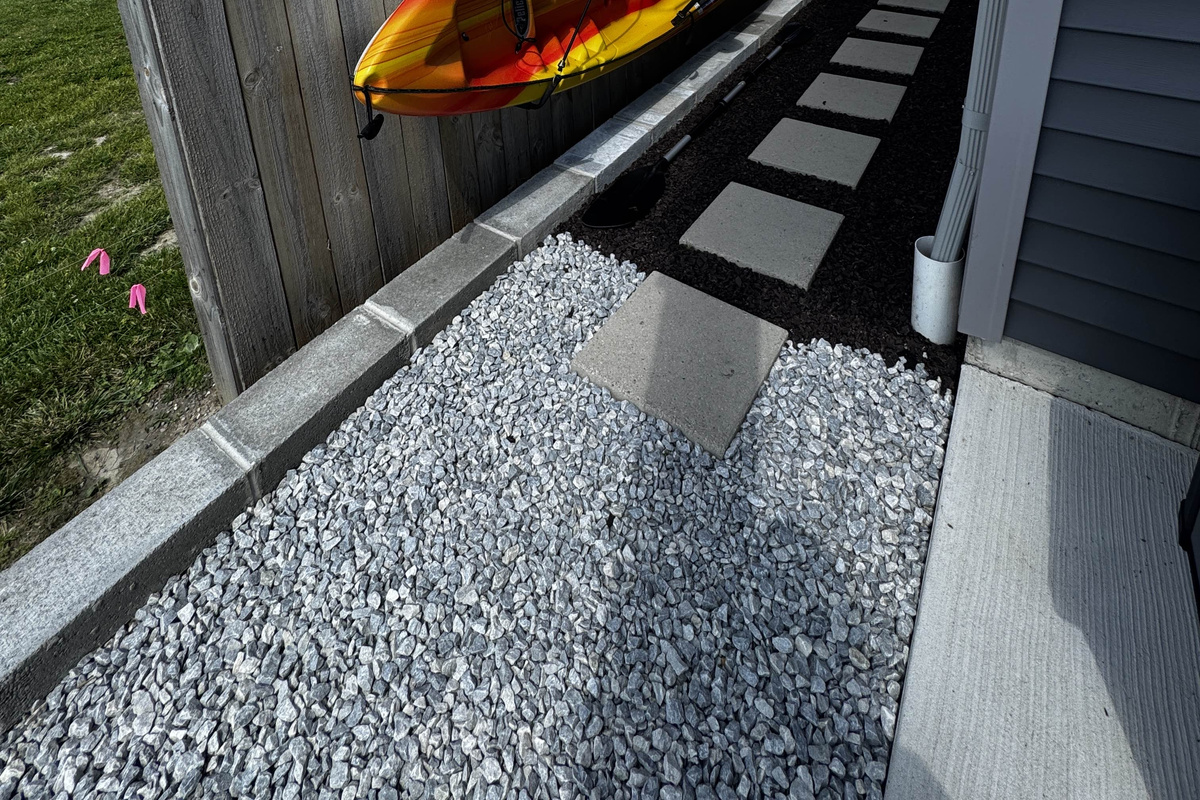 Clean side walkway with stepping stones and gravel path, connecting outdoor spaces along the waterfront home.