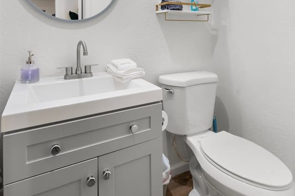 Modern vanity with round mirror and sleek lighting creates a bright, refreshing space.