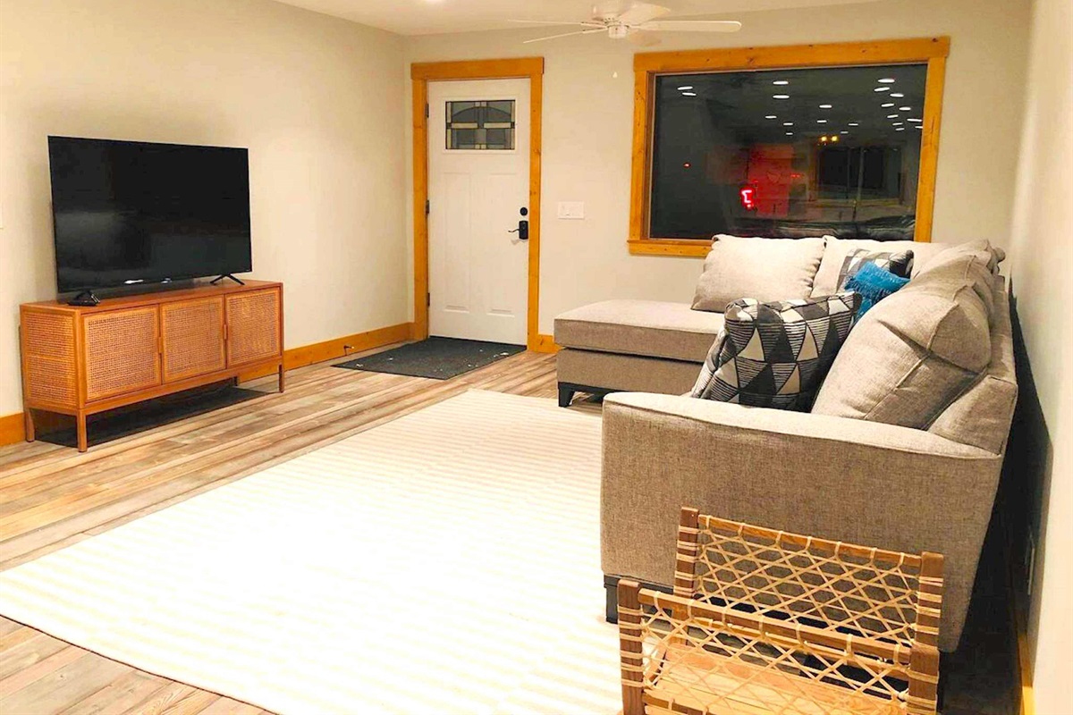 The inviting living room features a large TV and comfortable sectional. It's the perfect space for watching your favorite movies together or planning your upcoming adventures.