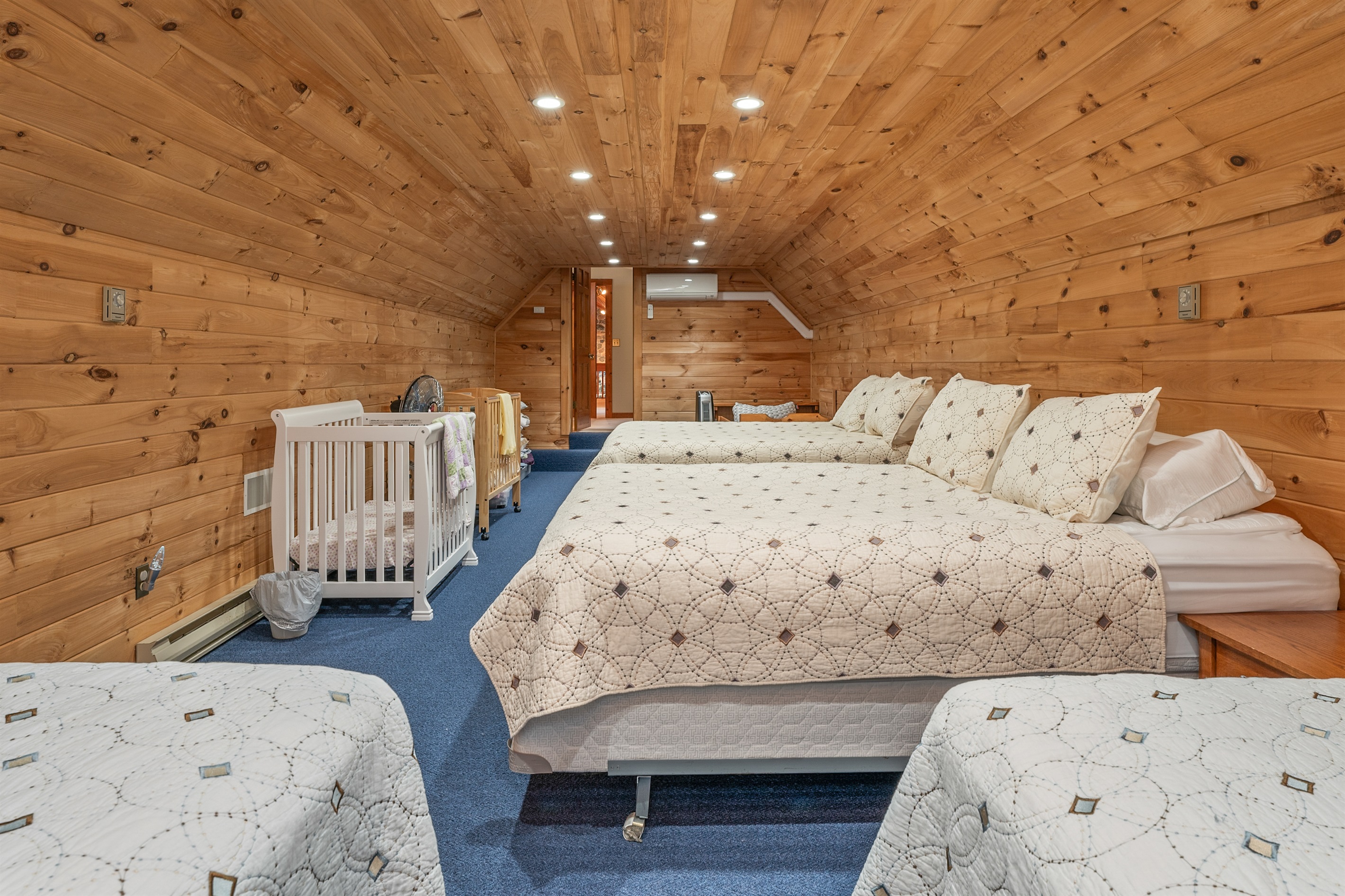 Inviting loft-style bedroom with cozy cabin vibes and vaulted wood ceilings.