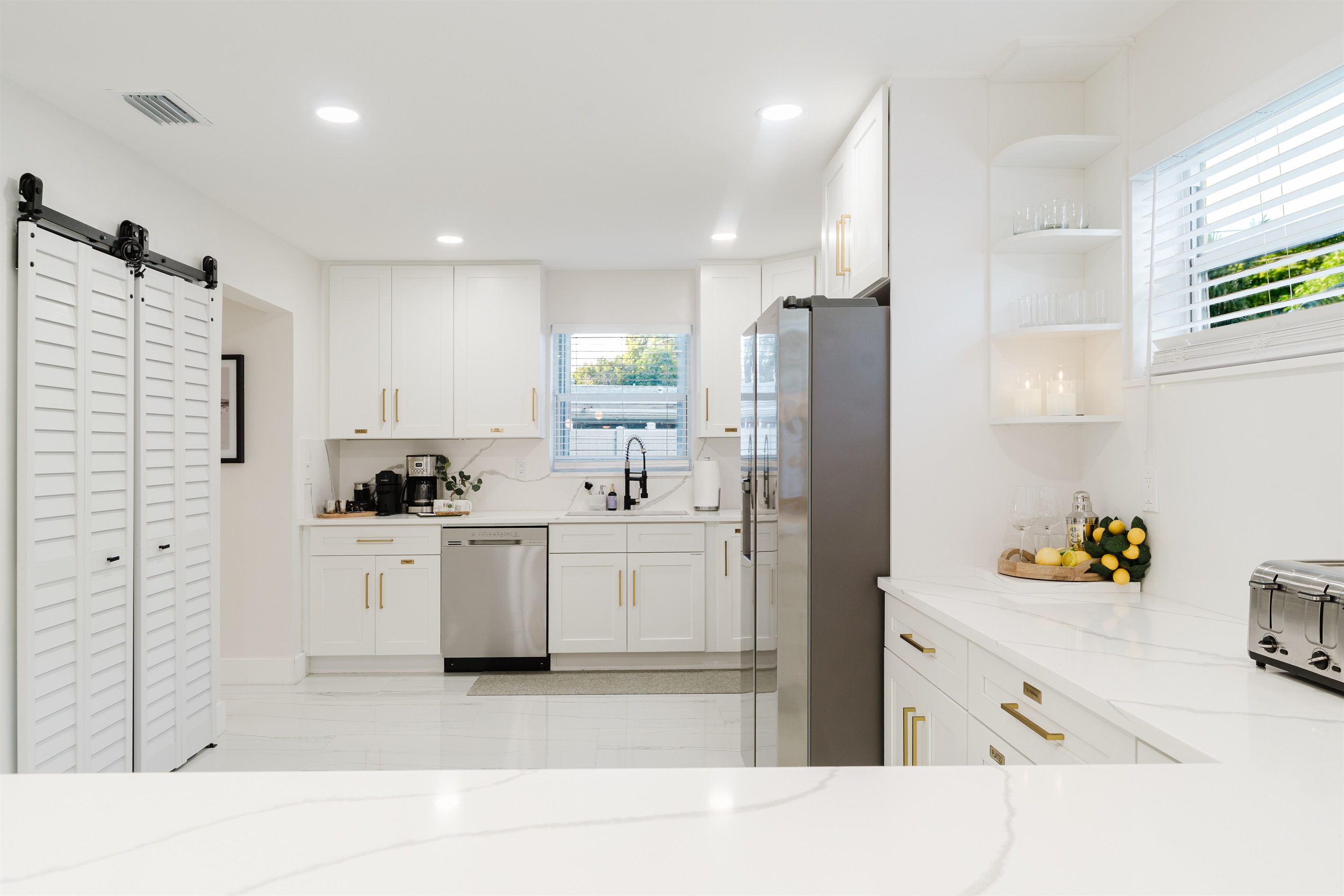 Bright, open-concept kitchen with quartz countertops, stainless steel appliances, and abundant prep space—perfect for family meals and entertaining. Fully stocked with a premium coffee setup, modern finishes, and seamless flow to dining and outdoor areas.