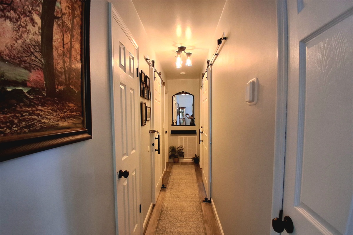 This is the hallway. Two bathrooms face each other, each equipped with sliding barn doors to optimize space. Additionally, there are two hallway closets—one housing the WiFi system and the other designated for cleaning supplies.