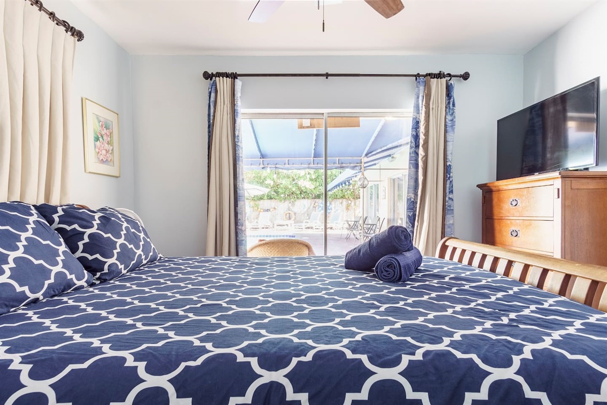 Bedroom #3 with direct Pool access, Queen sized bed, smart TV, ceiling fan, dresser and closet.