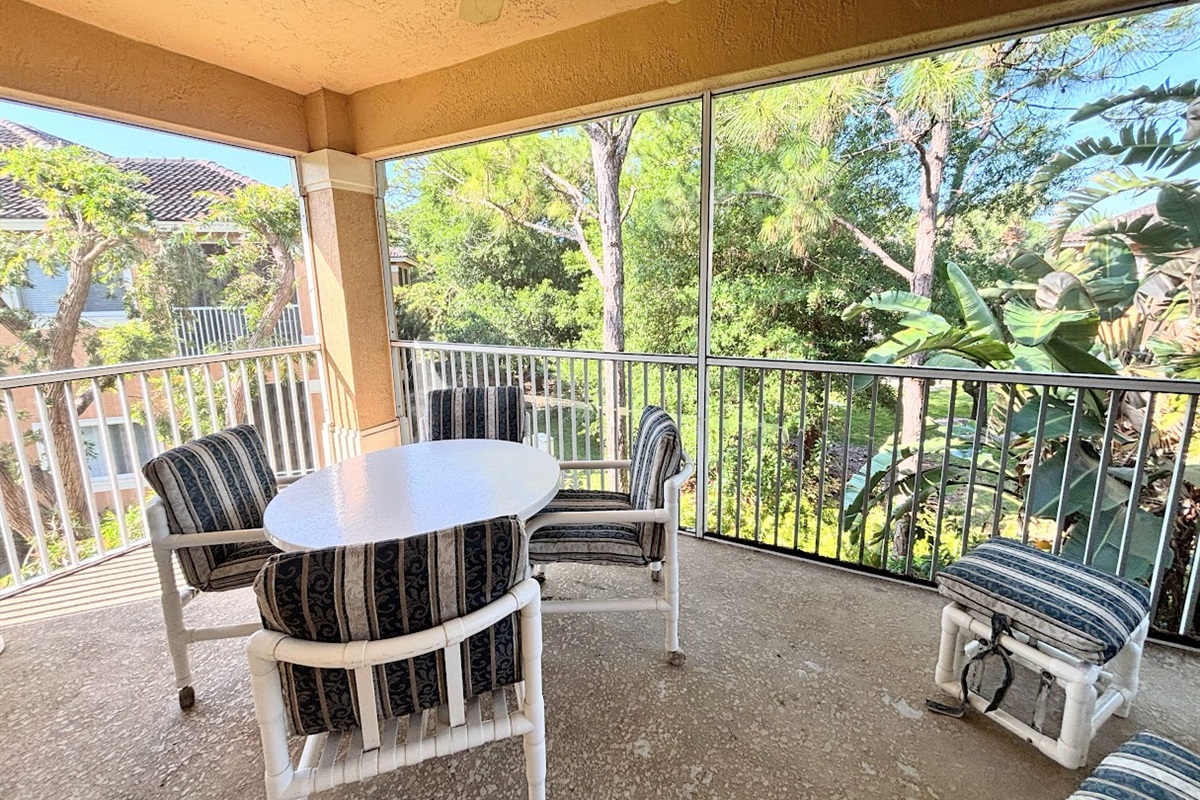 Private screened balcony with outdoor seating, offering a peaceful spot to relax and enjoy the surrounding greenery.
