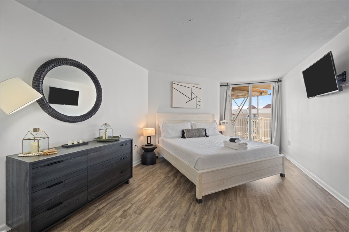 Serene Master bedroom with plush King bed, private balcony access, and calming coastal design