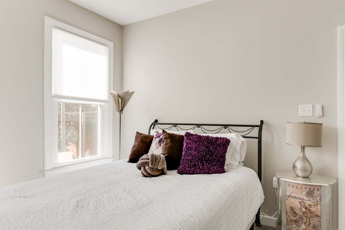 Queen Bedroom 3: Relax on a plush bed adorned with vibrant pillows and gentle natural light!