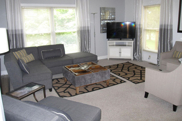 Far end of living room opposite the house entrance, sectional chairs and one of the TV's. 