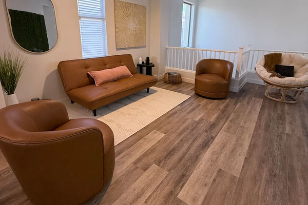 Open sitting area with accent chairs, sofa seating, natural light, and easy flow to the dining and living spaces.
