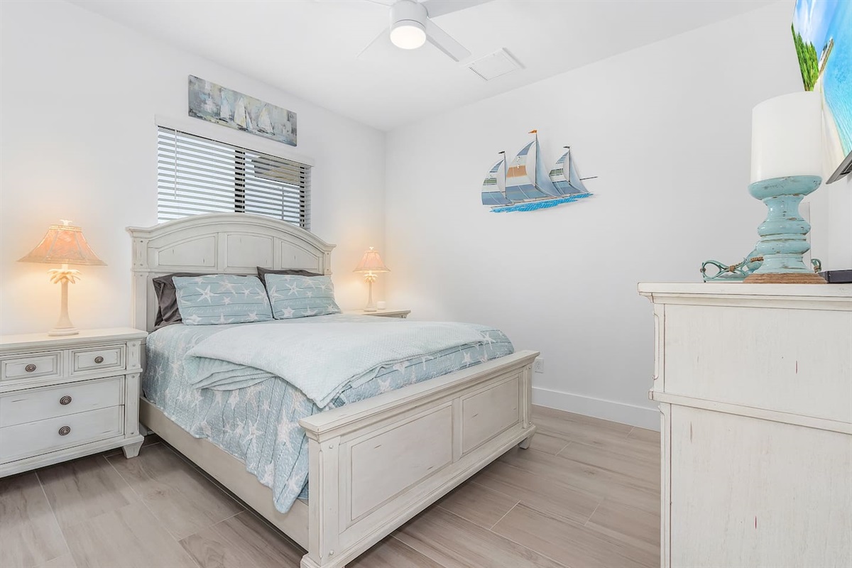 3rd Guest bedroom featuring a queen-sized bed, TV, and elegant coastal decor, providing a cozy and stylish retreat!