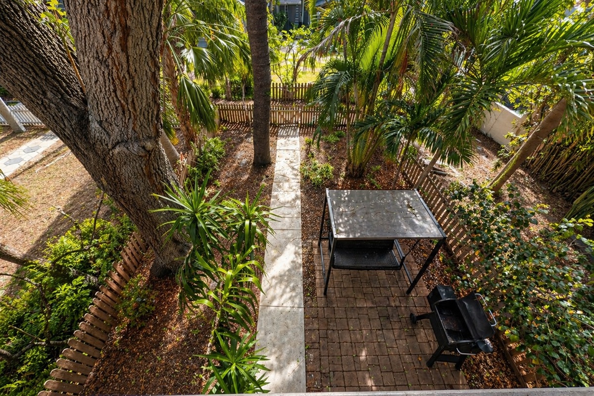 backyard with smoker, grill, swinging chair and fenced yard with Christmas lights at night 