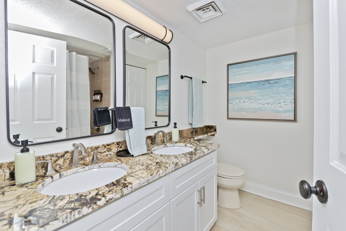 Bathroom stocked with shampoo, conditioner, body wash, plush towels, and first aid kit. 