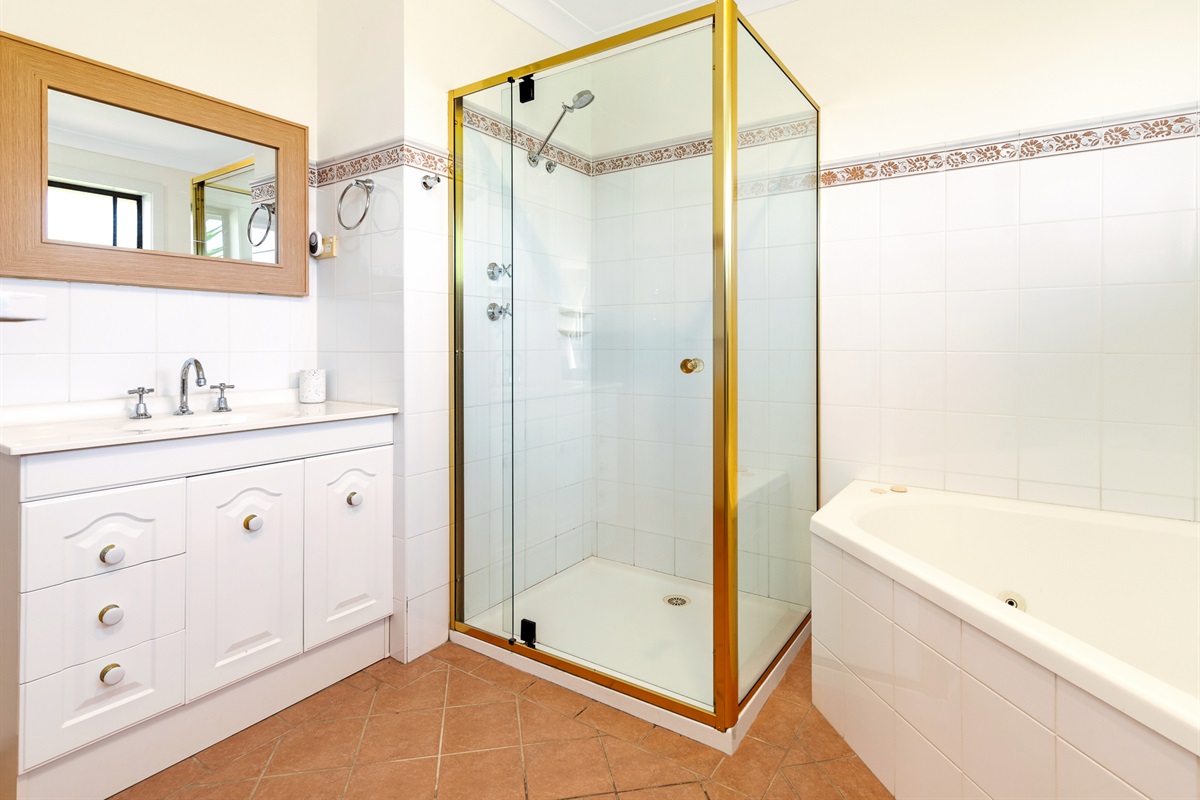A full-height shower screen, tiled floor and bright window make this upstairs bathroom a useful part of the main-level layout.
