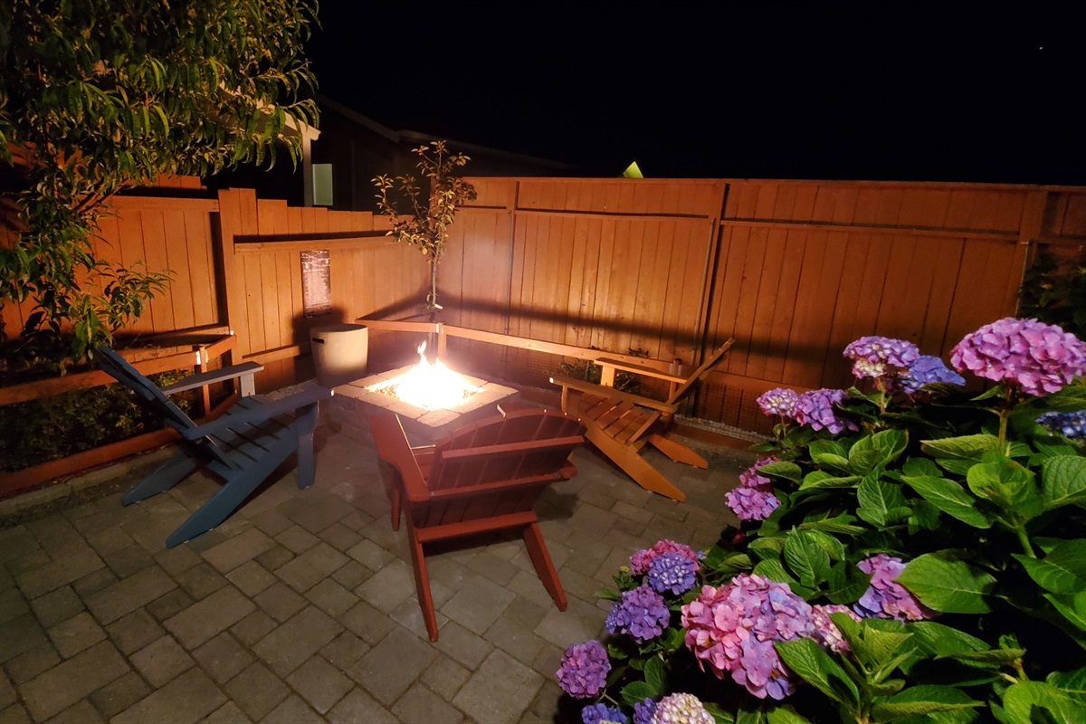 Propane-fueled stone fire pit warms coastal evenings through shimmering copper fire glass