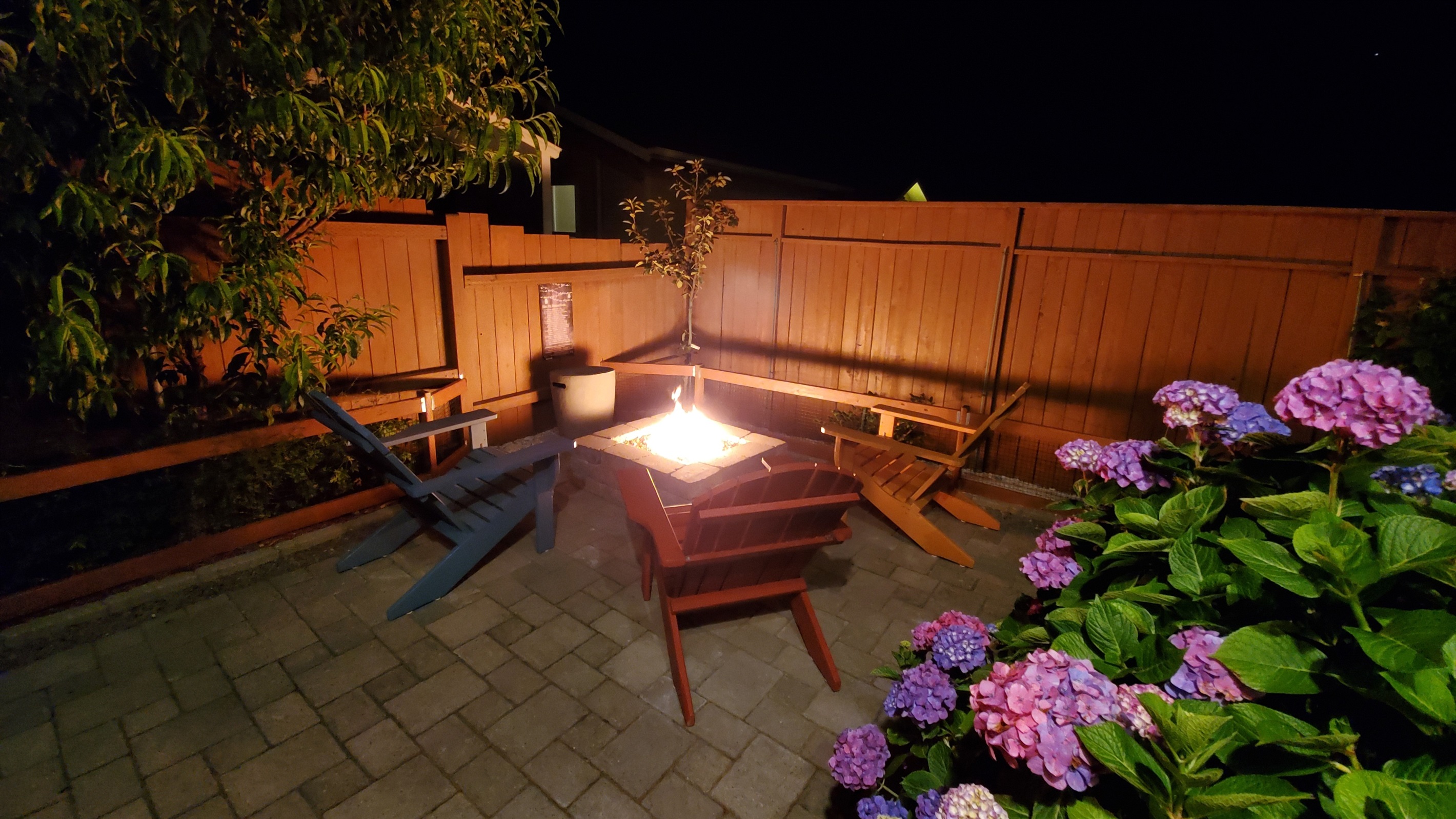 Propane-fueled stone fire pit warms coastal evenings through shimmering copper fire glass