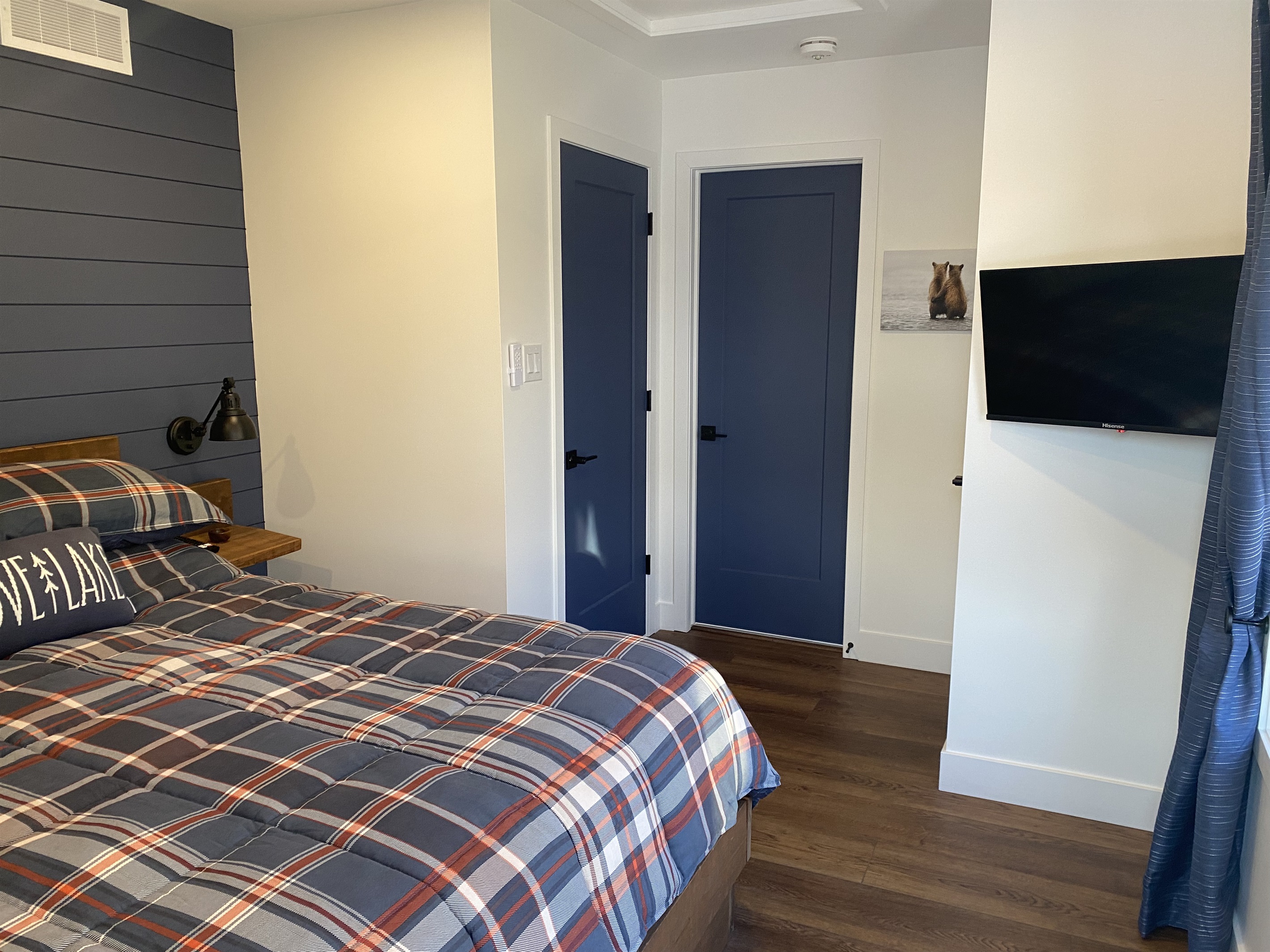 Main floor 2nd bedroom with queen bed, smart TV, closet door and entrance door from hallway