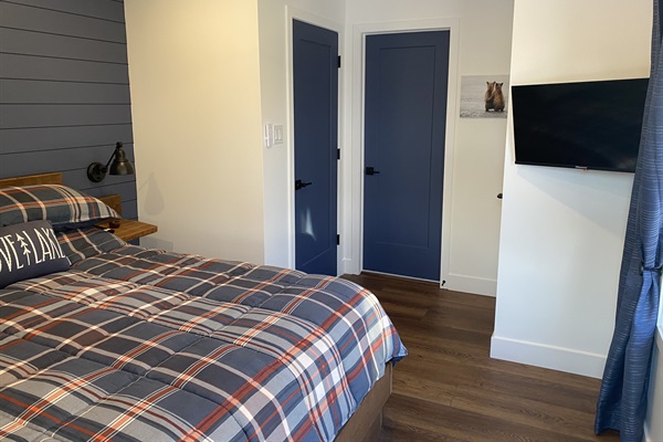 Main floor 2nd bedroom with queen bed, smart TV, closet door and entrance door from hallway