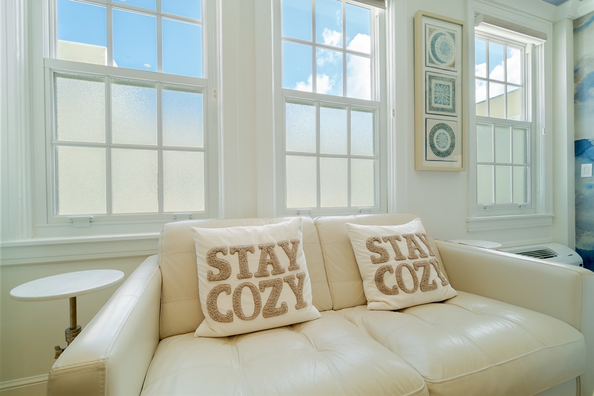 Leather sofa with "Stay Cozy" pillows.
