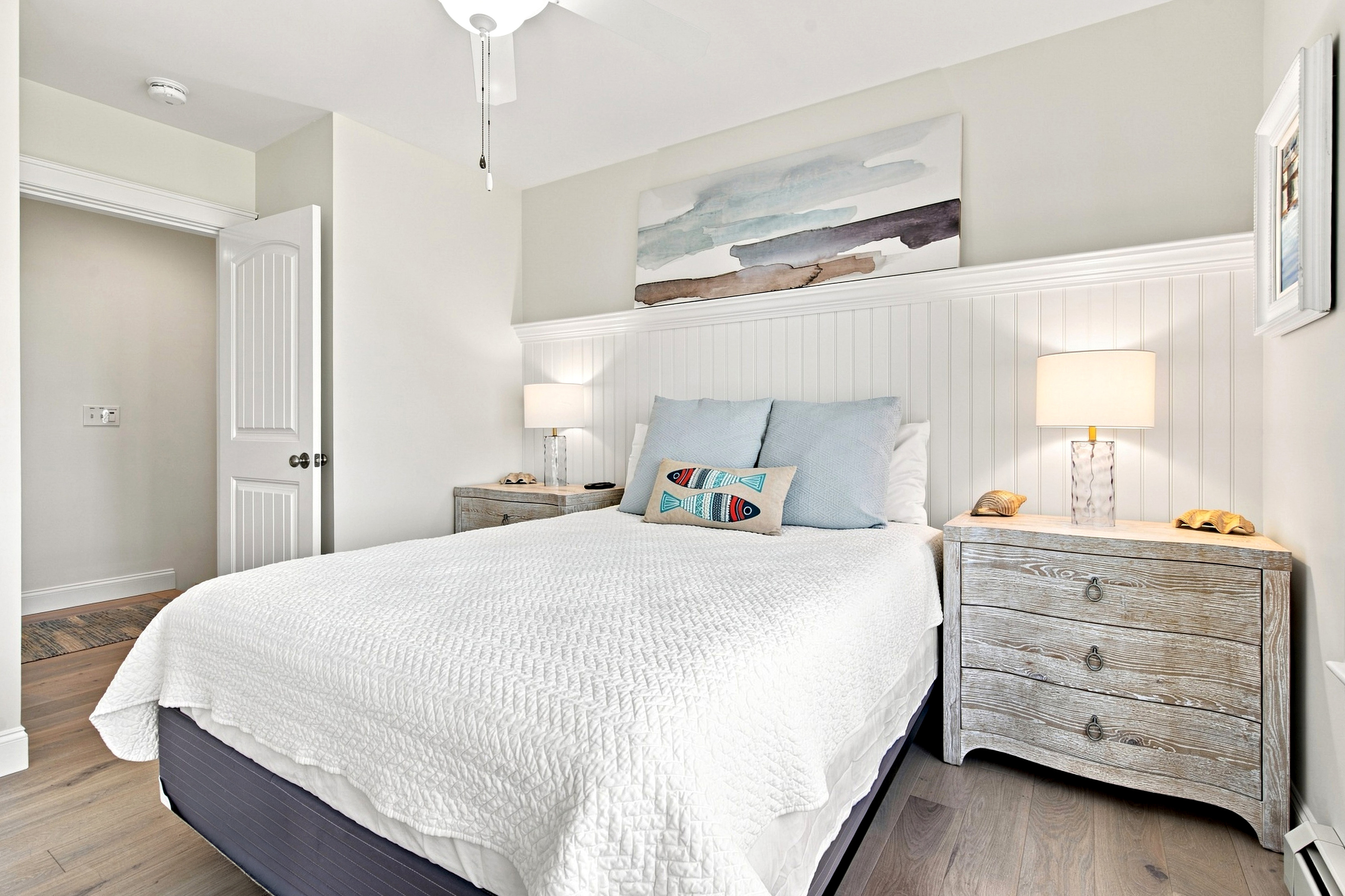 Unwind in a peaceful bedroom featuring comfortable bedding and calming coastal-inspired décor.