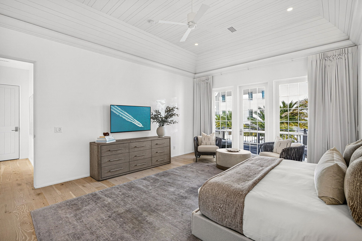 The primary suite offers a great seating area, large dresser, wall mounted Smart TV, and private access to the porch overlooking the pool.