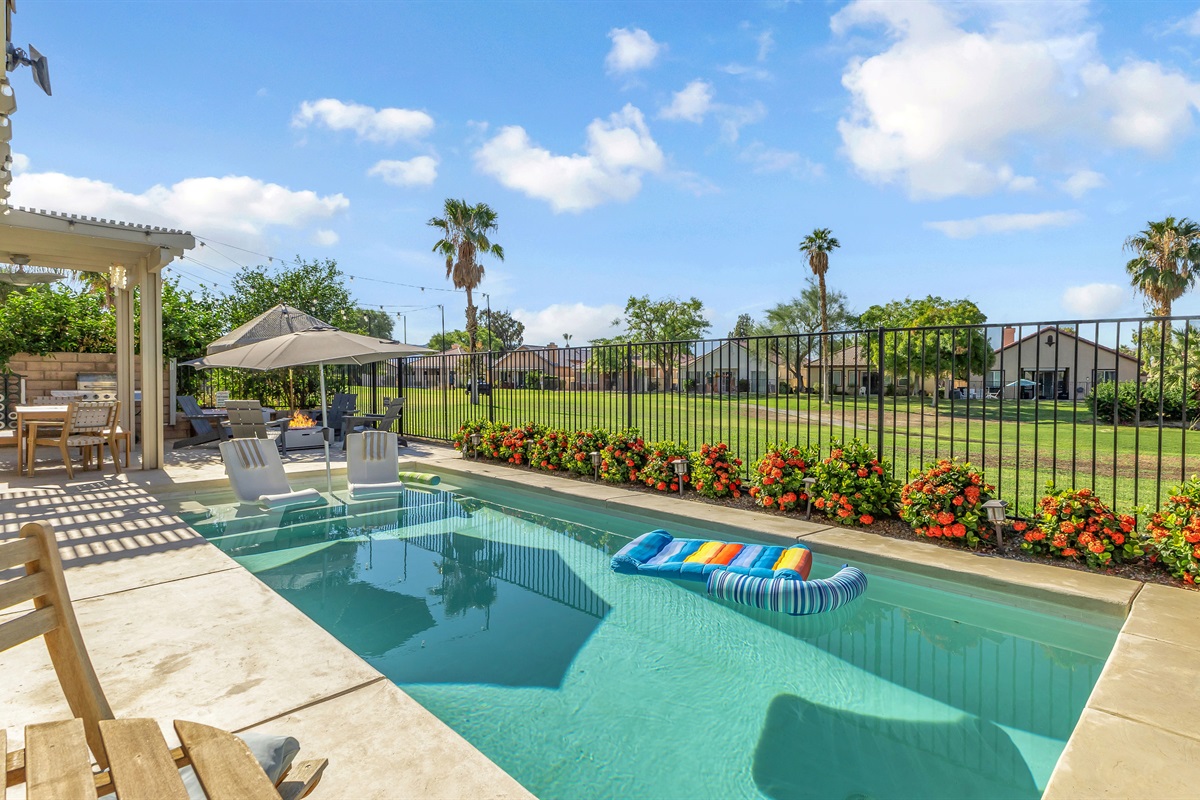 🏖️ Relaxation Meets Style Beautifully landscaped pool area with vibrant flowers and comfortable seating, designed for relaxation and outdoor fun.
