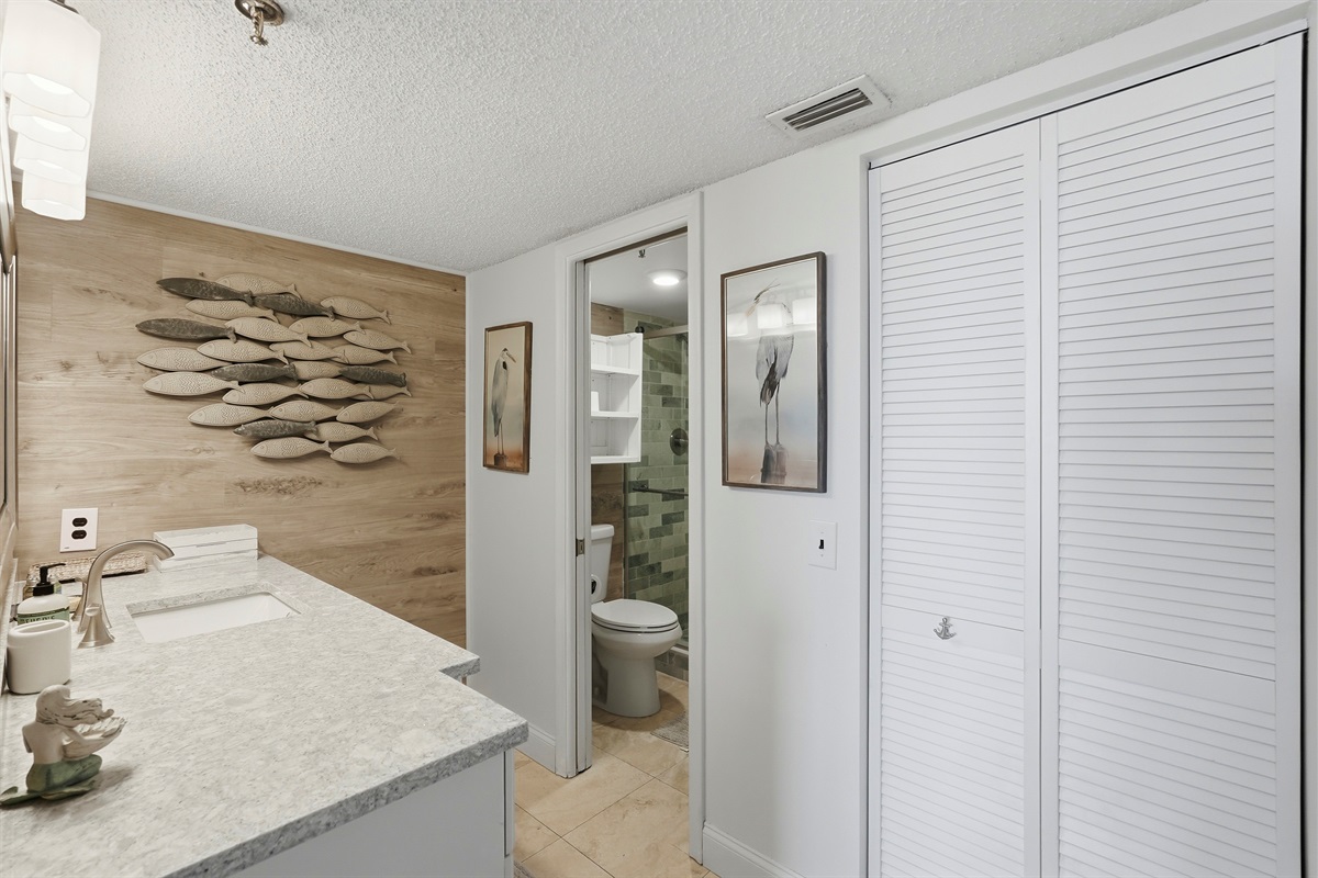 The common bathroom offers a clean, functional layout with a walk-in shower, toilet, and vanity. It also includes plenty of closet and storage space, providing added convenience for guests during their stay.