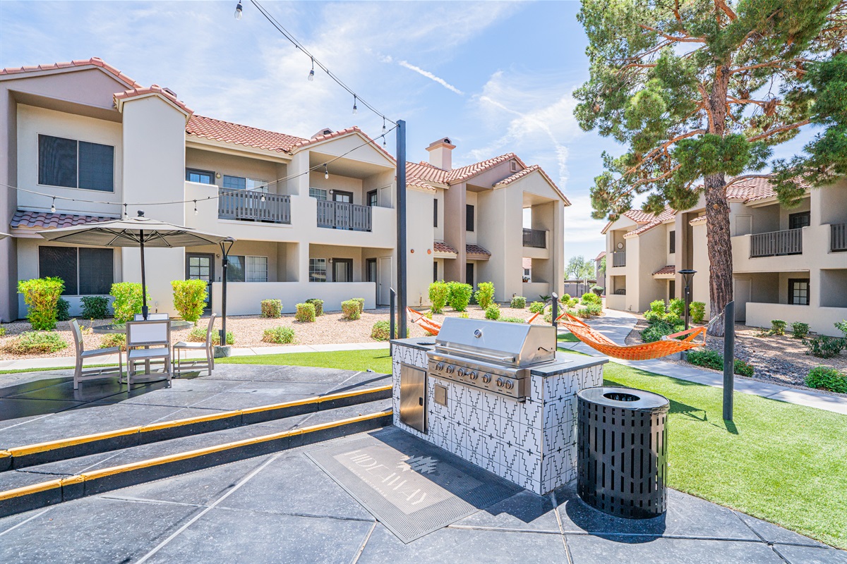 Vibrant courtyard with games, string lights, and lush green space for fun and relaxation.