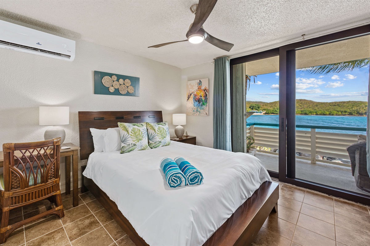 Primary bedroom with queen bed and access to the balcony, AC unit, and desk
