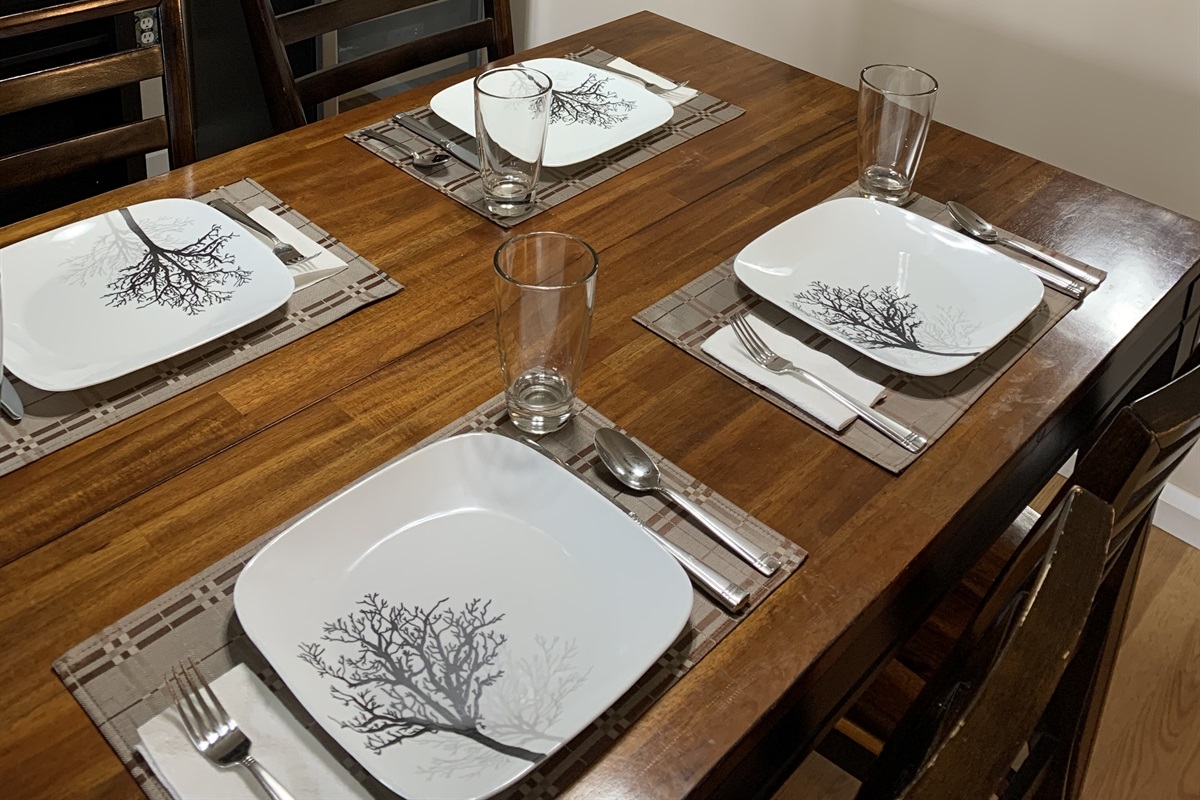 Spacious dining room with large table. Place setting for 4 guests.