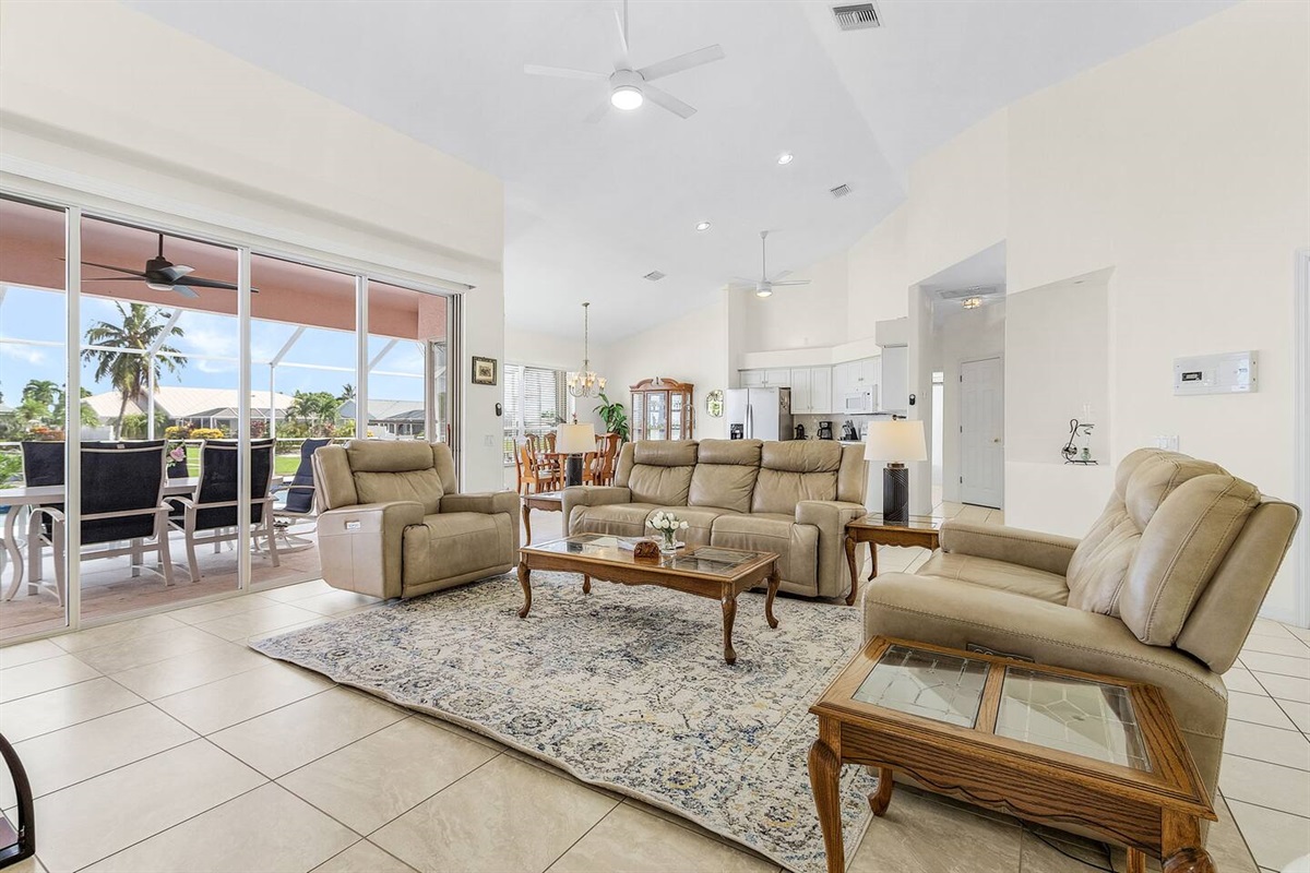Spacious living room with cozy seating and a TV, offering seamless access to the pool, spa, and lanai for ultimate relaxation and fun!