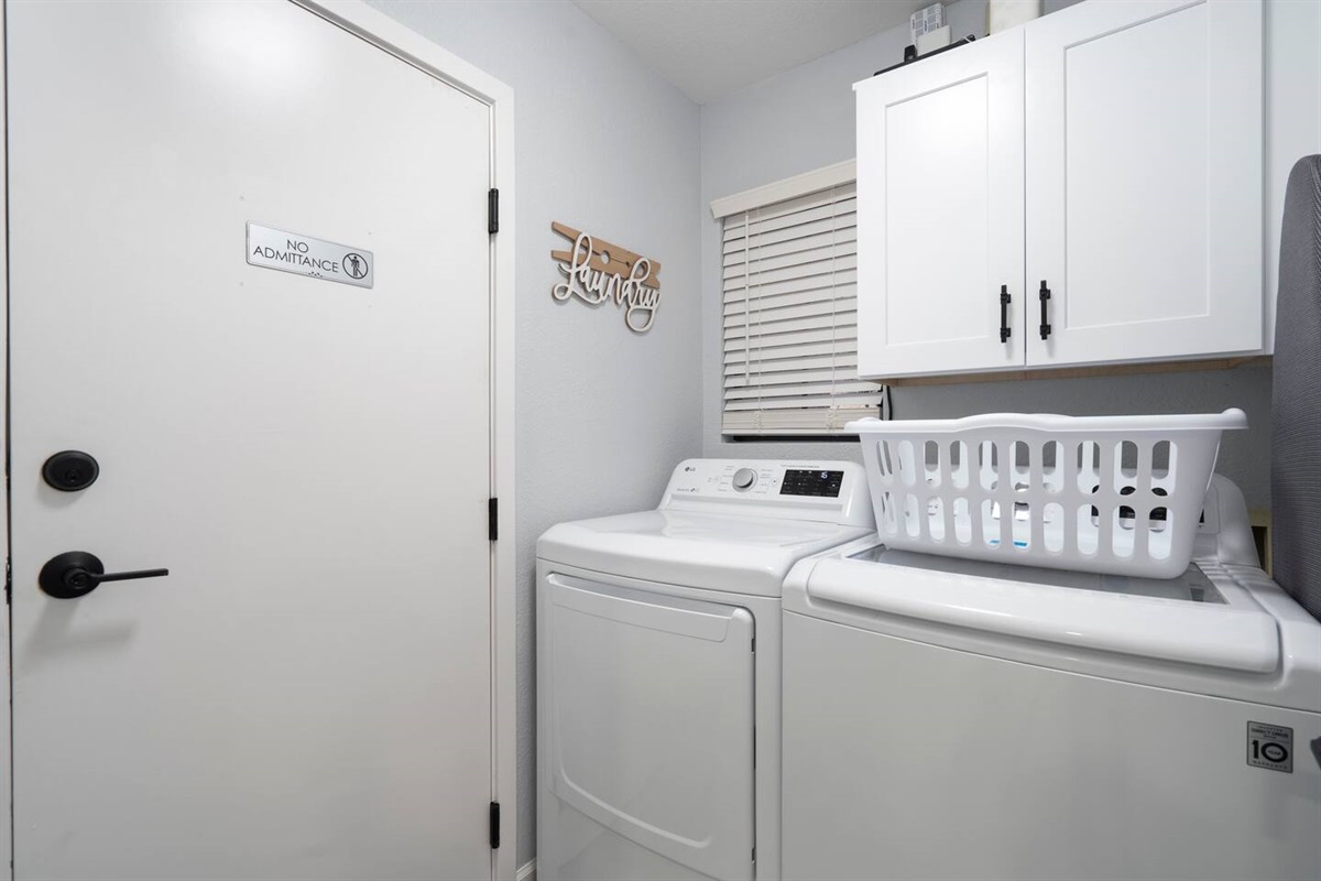 Laundry room with detergent and bleach provided. Open the cupboard to find the iron, first aid kit, small sewing kit and fire extinguisher. Ironing board is up against the wall, next to the washer.