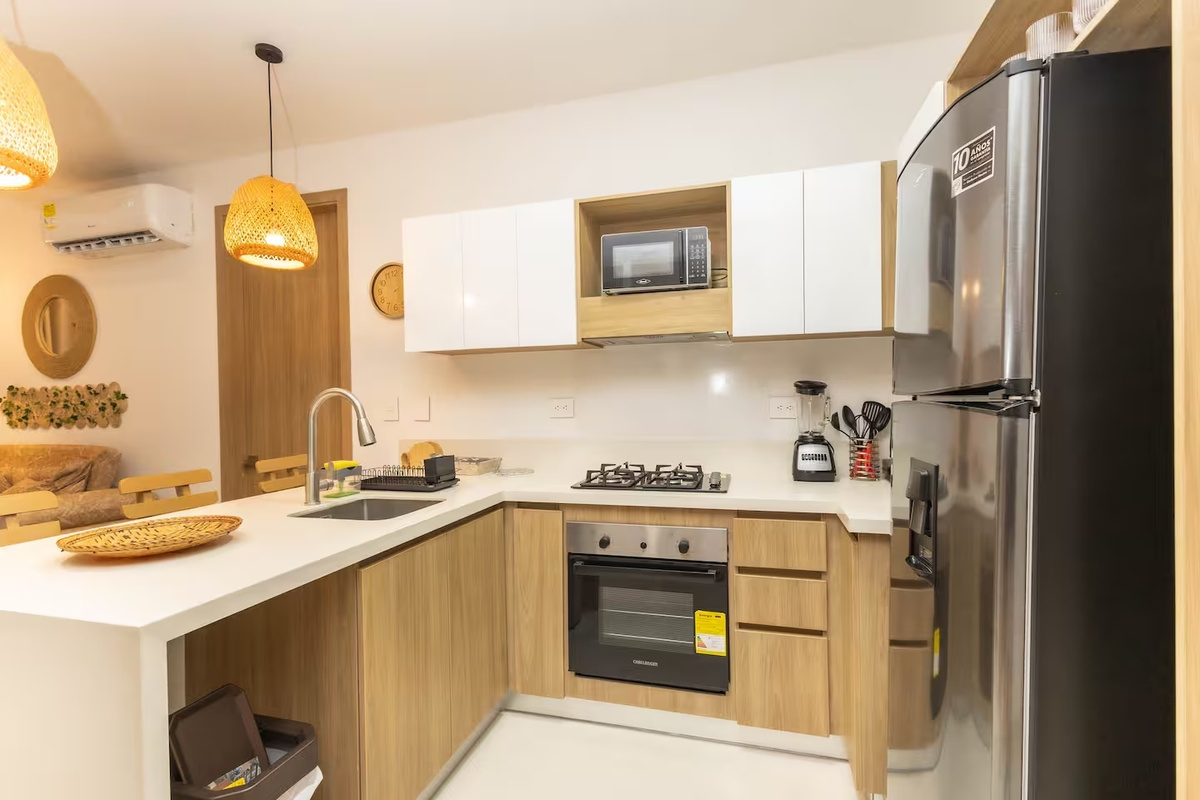 Cocina abierta y barra de desayuno con estufa de gas, refrigerador de tamaño completo, microondas y estación de café para preparar comidas de forma sencilla durante la estancia.