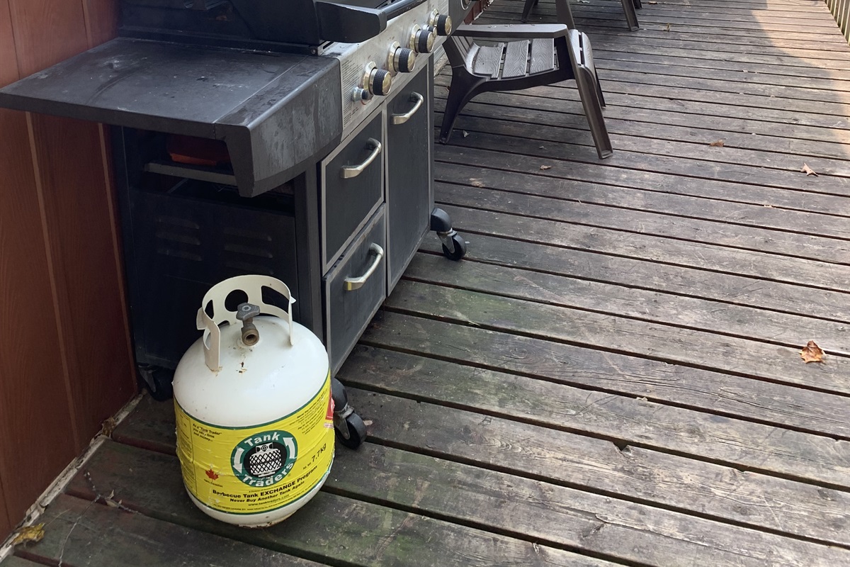 Propane BBQ is located close to both cottage doors for easy access to kitchen and dining area