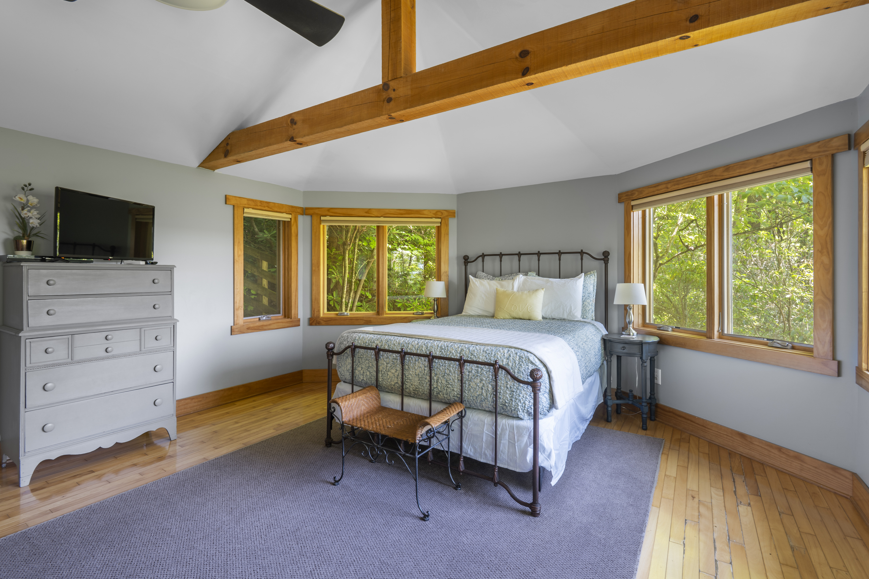 Queen-sized bed flanked by windows and the privacy of natural surroundings