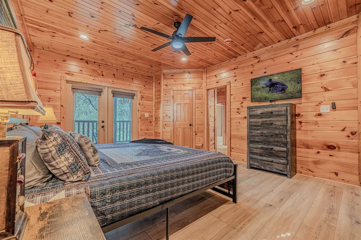 Lower-level king bedroom with private en-suite bath and deck access. The Crown Jewel &mdash; 5BR/5BA luxury cabin in Gatlinburg, TN. Sleeps 12.