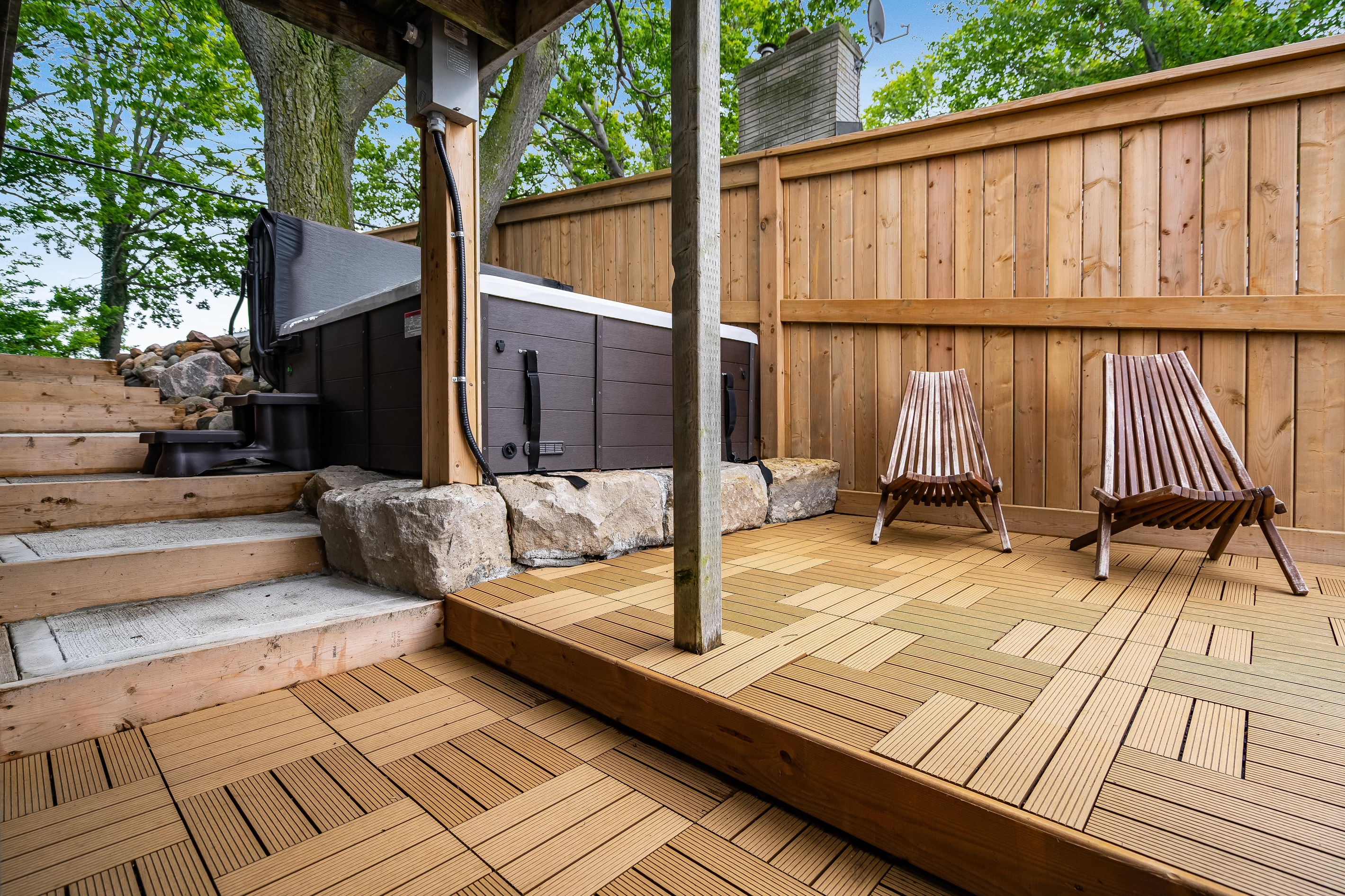 Relaxing outdoor spa area with a hot tub, privacy fencing, and inviting lounge chairs.