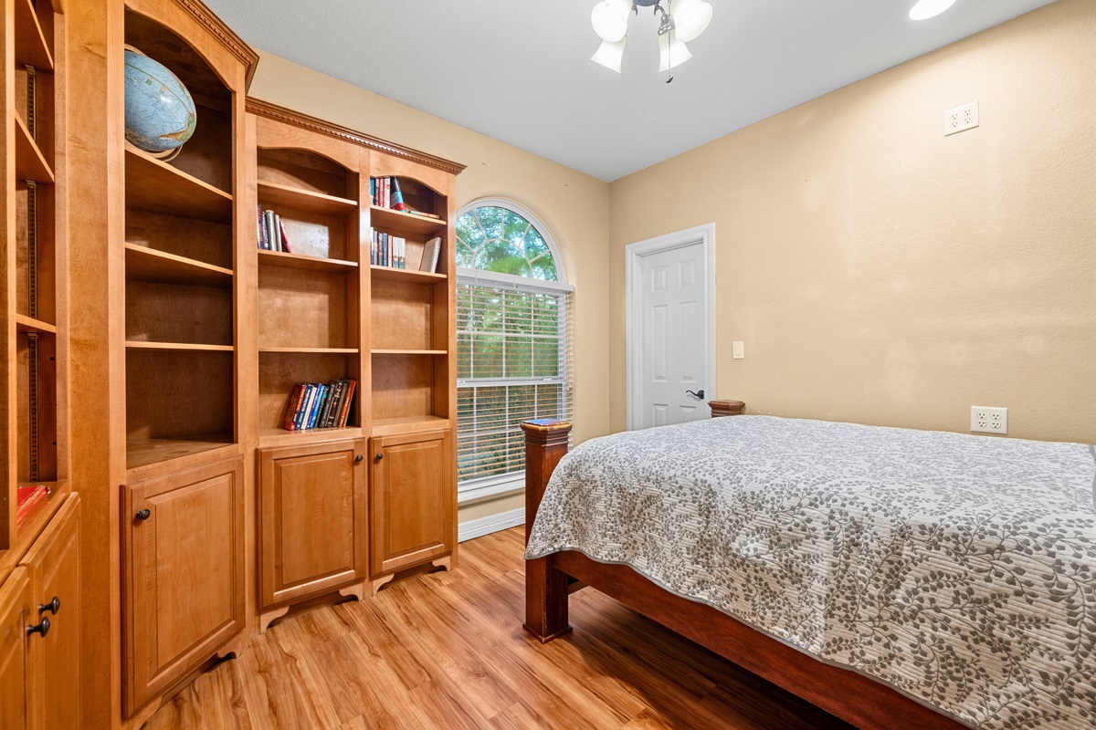 Queen bedroom with custom built-ins and bright windows.
