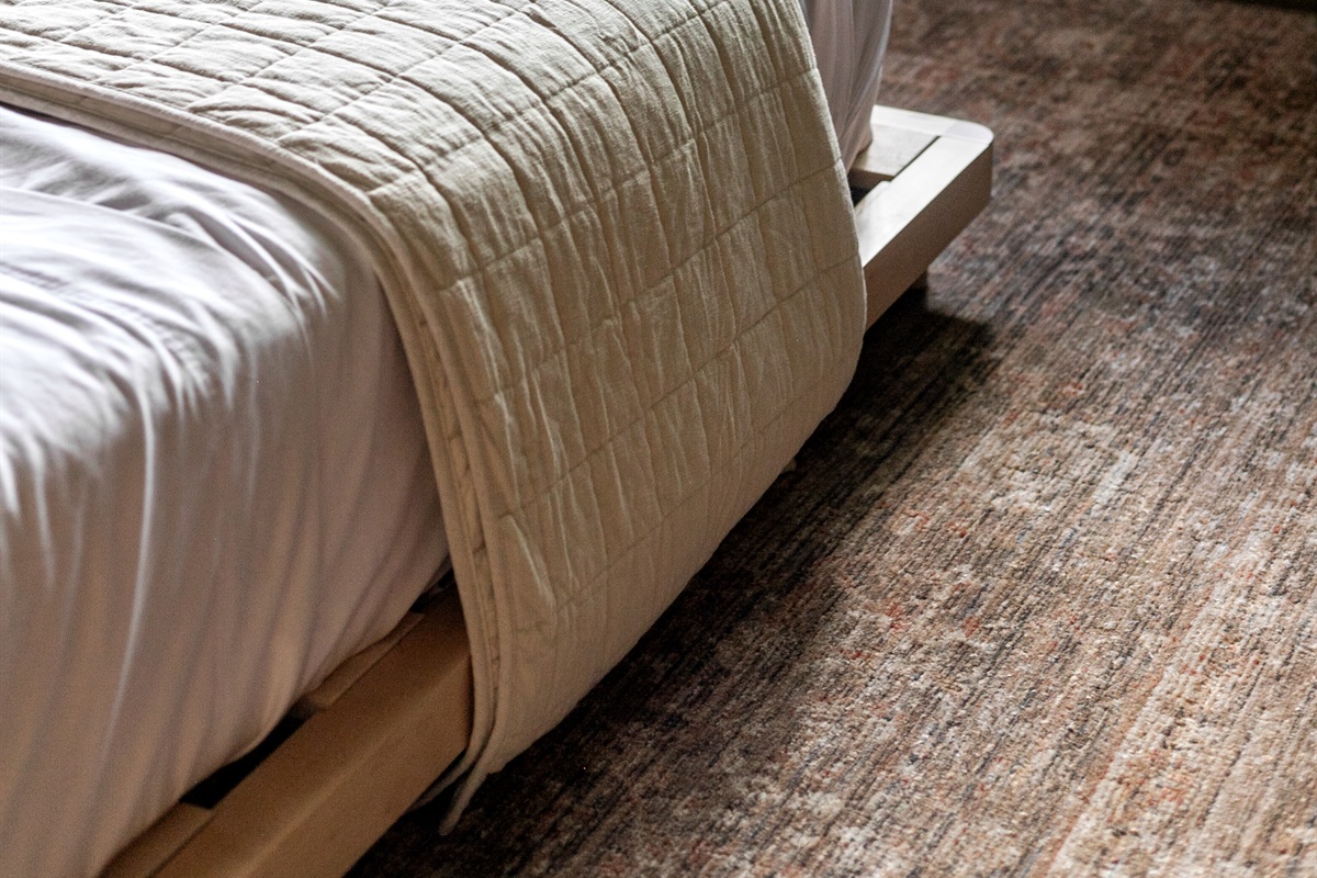 This queen-size bedroom combines cozy design with modern simplicity. The low platform bed creates a sleek, inviting look, while bedside tables and a lamp add convenience.
