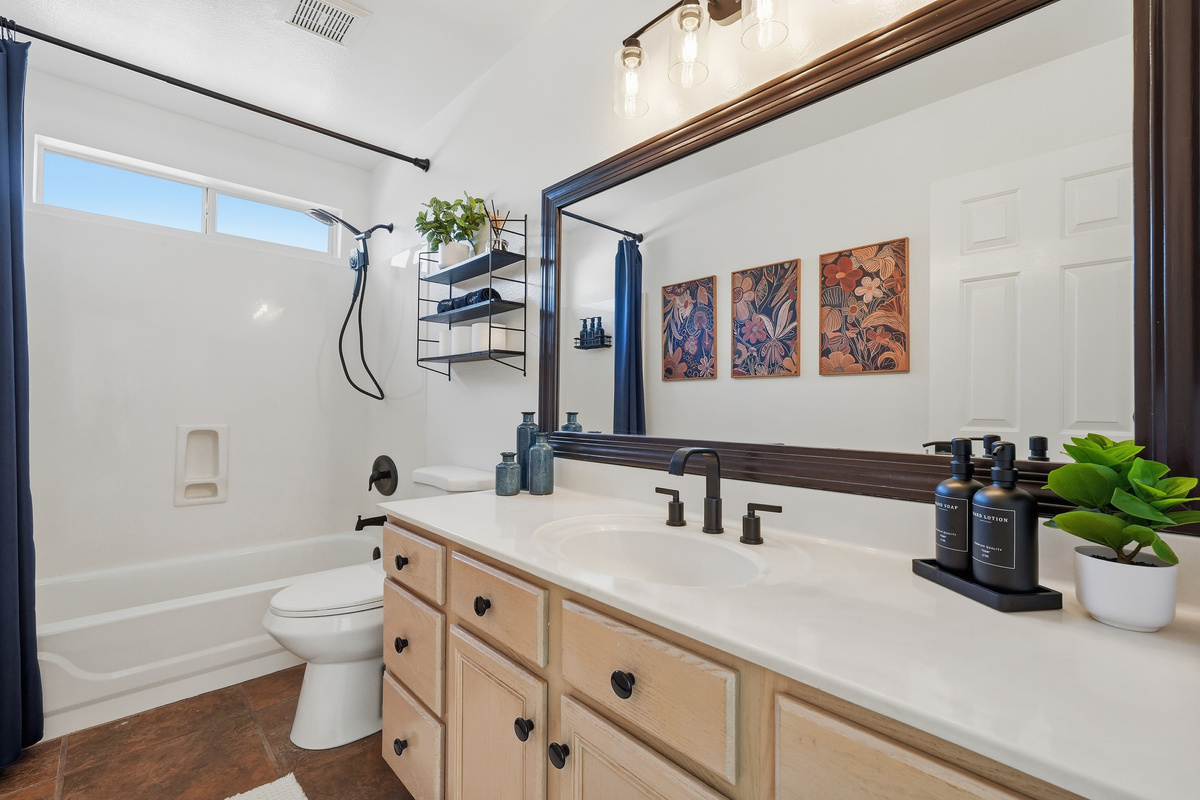 Full Bathroom 2 with shower/tub combination, vanity storage, bright mirror lighting, and clean essentials for daily routines.