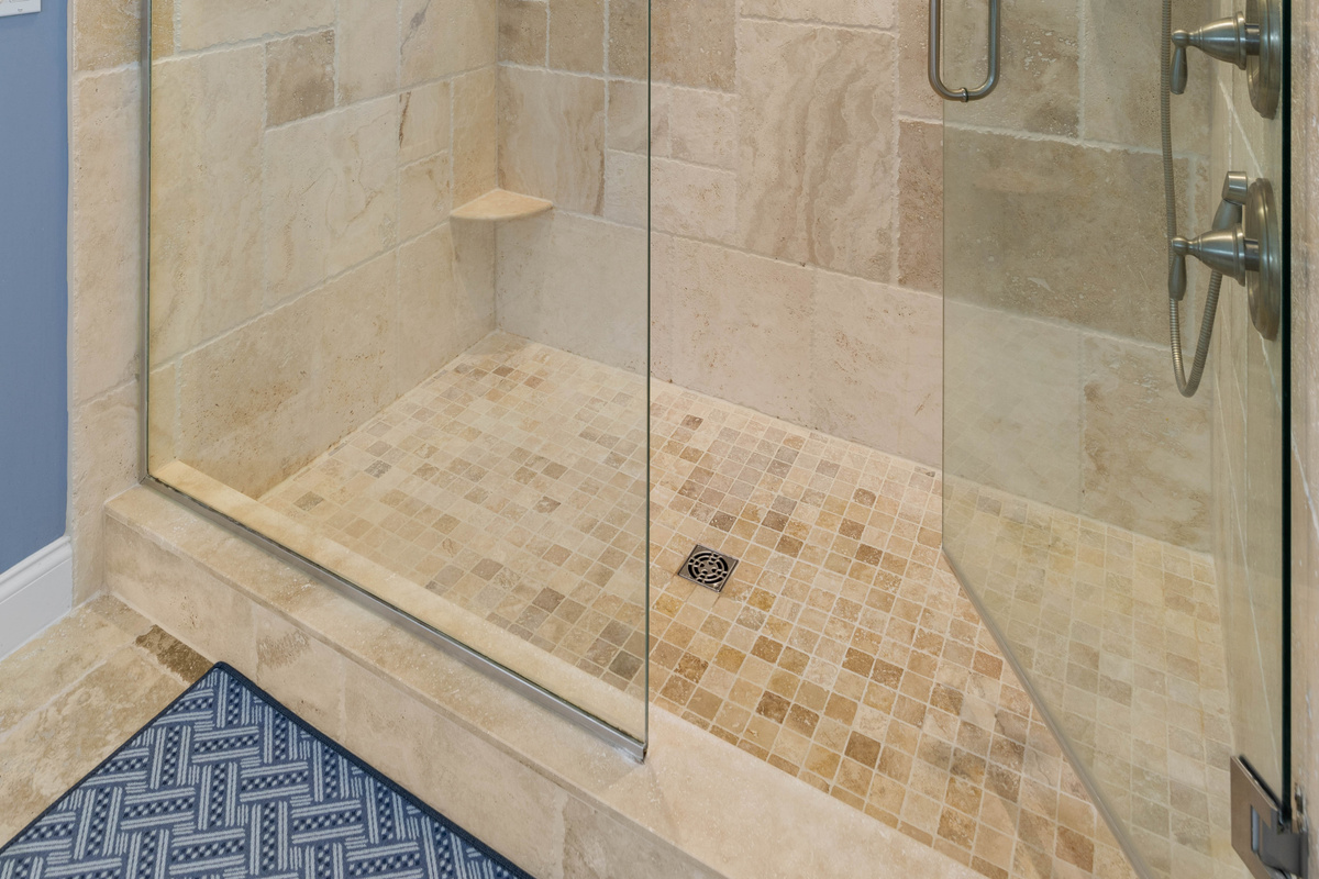 Inside the walk-in shower: dual controls, a handheld sprayer and a corner shelf, handy for rinsing off sandy feet.