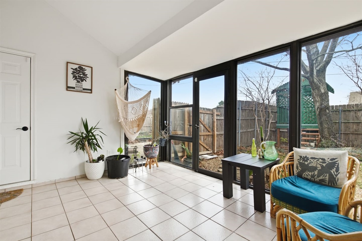 Bright sunroom with floor-to-ceiling windows, seating area, and relaxing natural light.