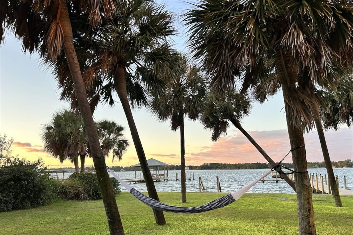 Peaceful sunset hammock retreat by the lake with palm trees and tranquil vibes.
