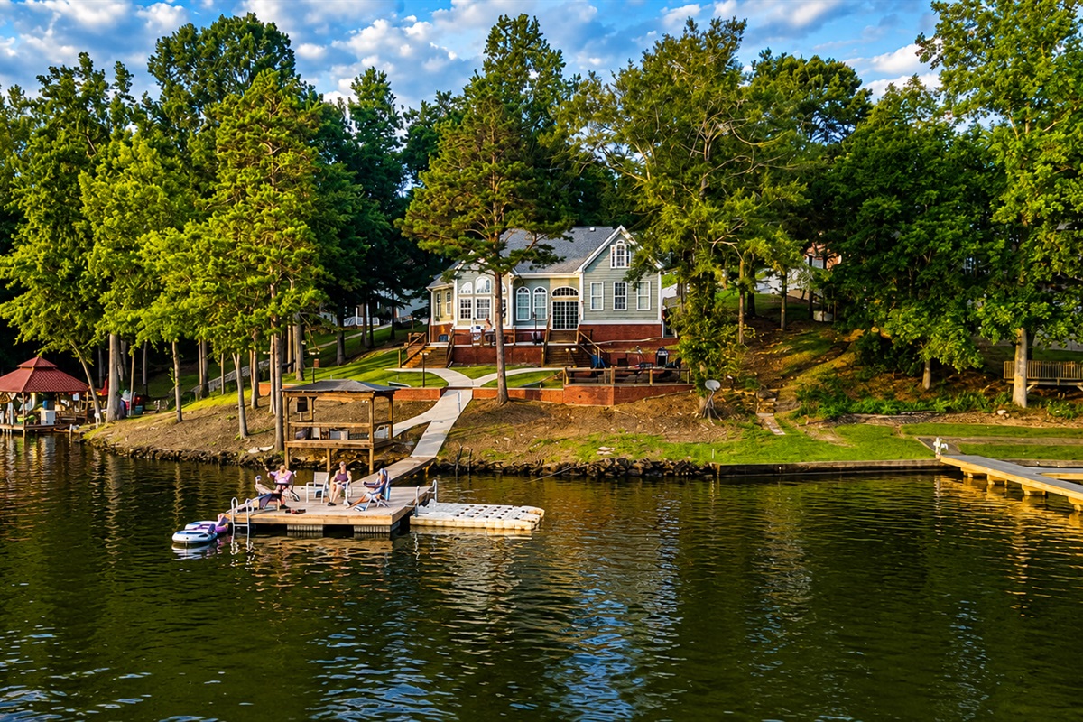 An aerial perspective captured by a drone, showcasing the cabin along with its charming dock and the serene beauty of the lake.