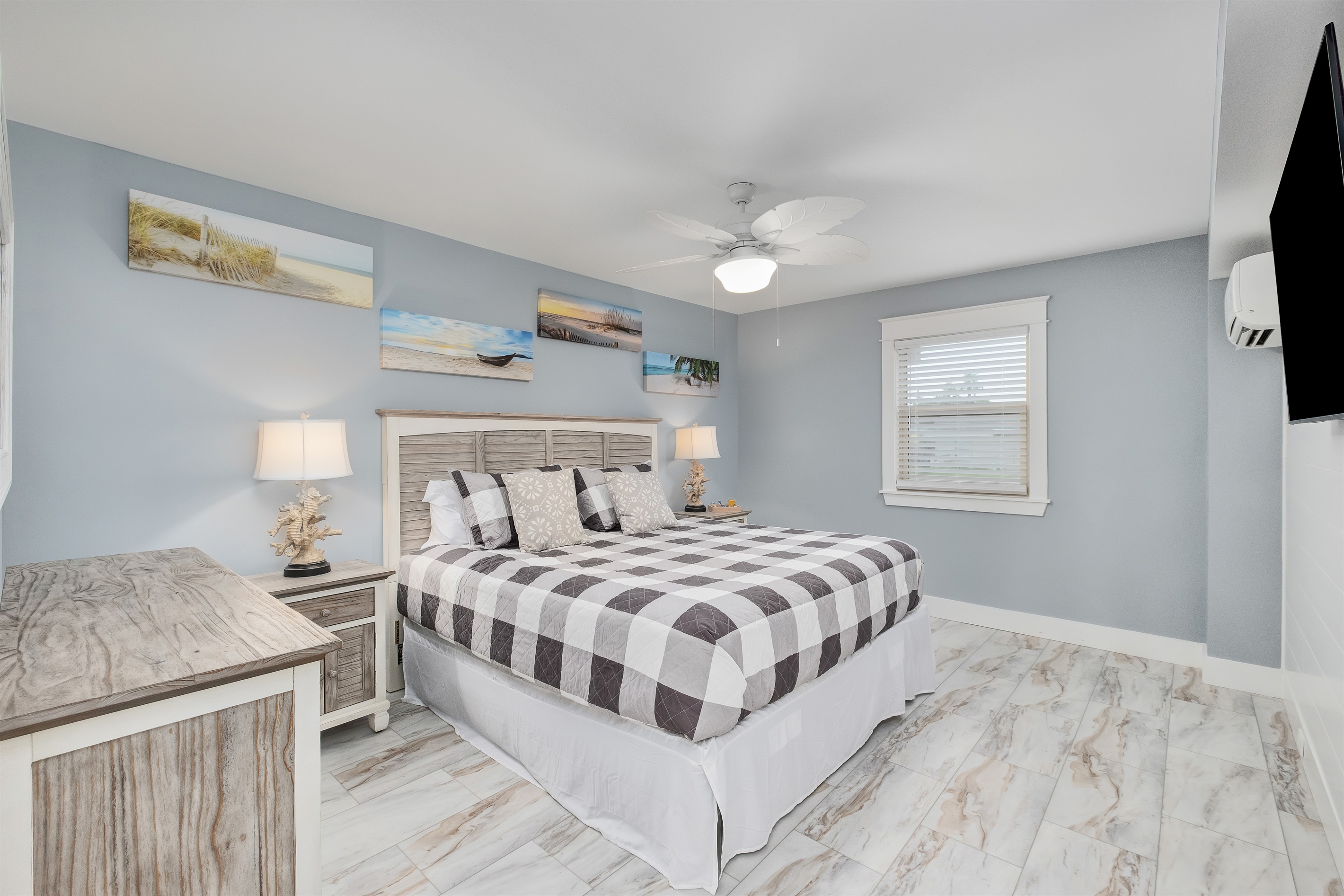 Unwind in the comfortable master bedroom featuring a king bed and beach-themed decor.