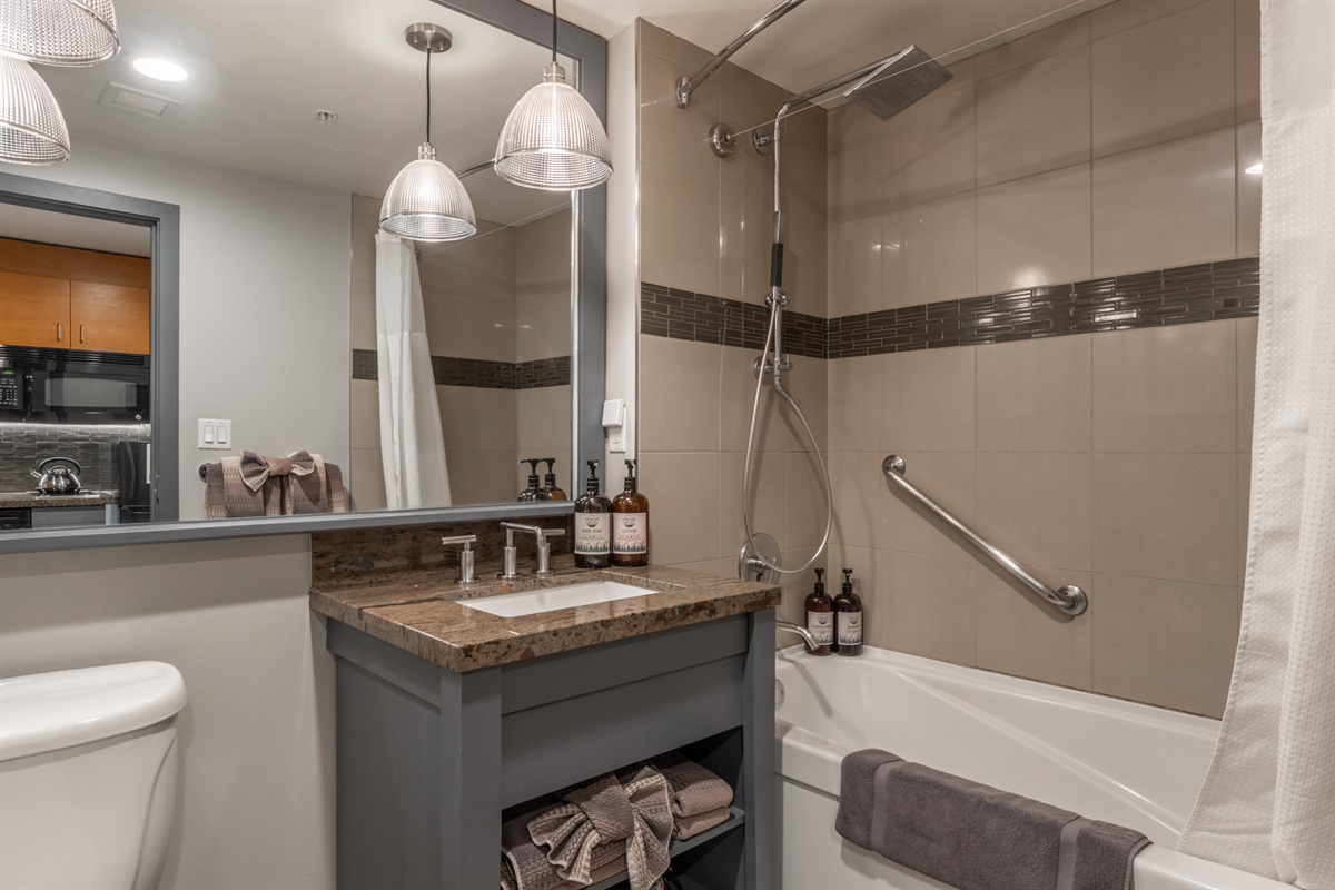 The bathroom features clean white tile, a tub/shower combo, and a modern layout designed for comfort and ease.