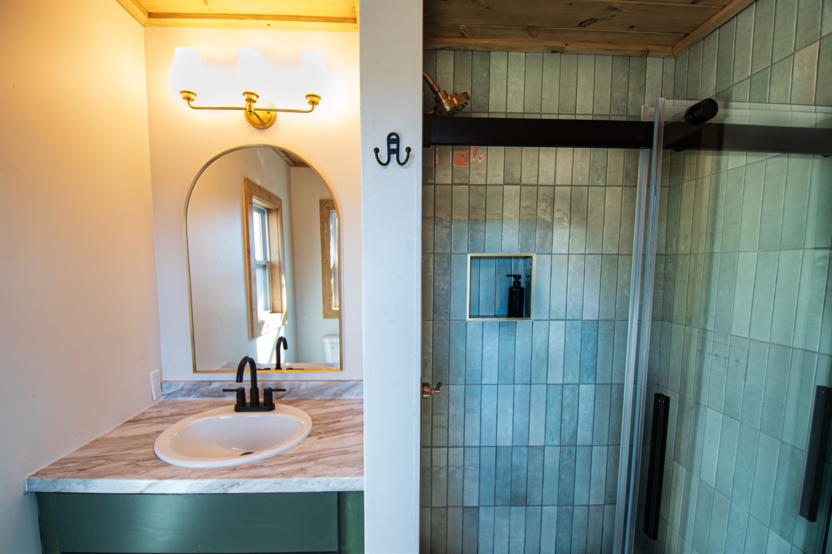 Downstairs, the second bathroom has a walk-in glass shower with custom tile and our tankless hot water heater will keep those showers steamy!