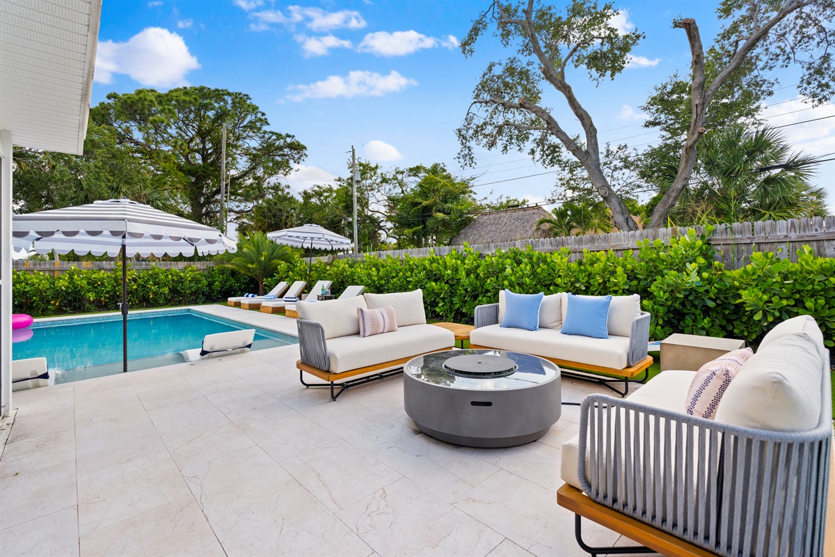 Resort-style outdoor living with luxe lounge seating, lush landscaping, and a sparkling private pool oasis.