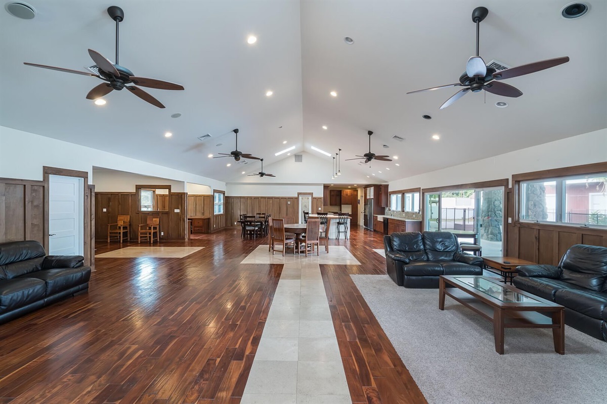 Step into this expansive living area with dark wood flooring, sleek leather sofas, and contemporary ceiling fans