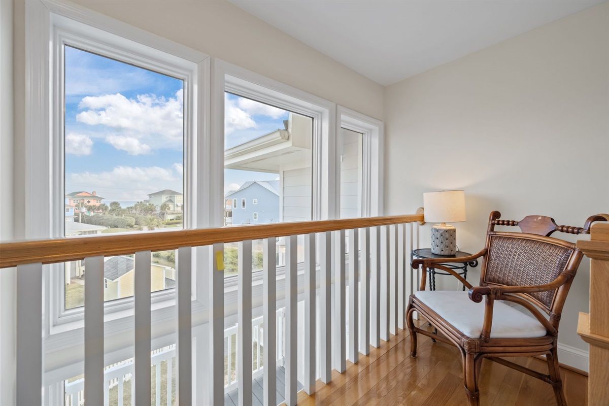 Cozy upstairs landing with seating and bright coastal views